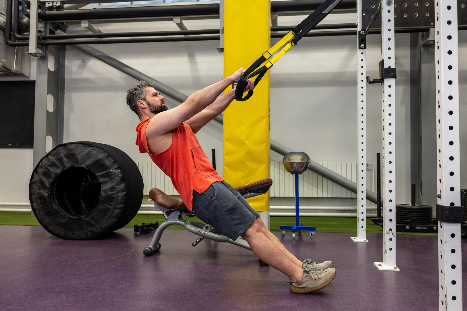Muscular man doing exercise with TRX, functional workout for body at gym.